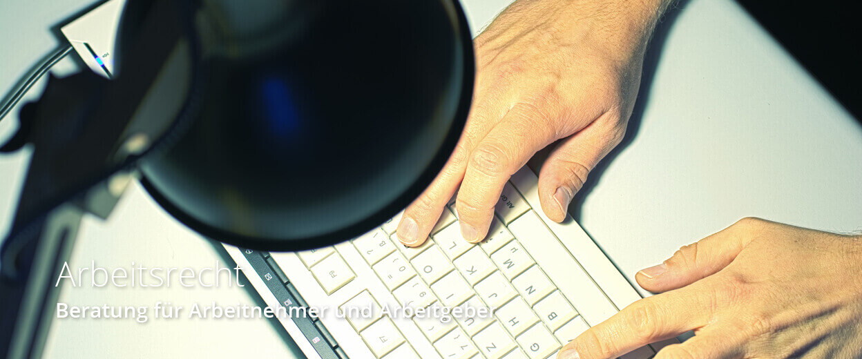 Zwei Hände tippen konzentriert auf einer Tastatur unter einem Schreibtischlampenlicht, während rechtliche Informationen bearbeitet werden.